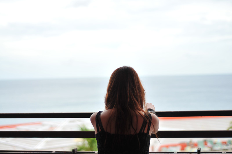 woman looking over balcony at ocean